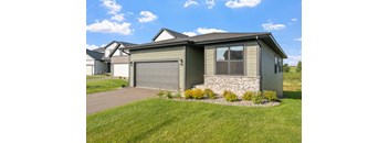 a green house with a driveway and a garage door