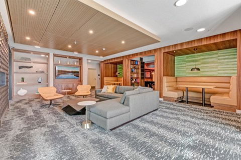 A modern living room with a grey carpet and a wooden ceiling.