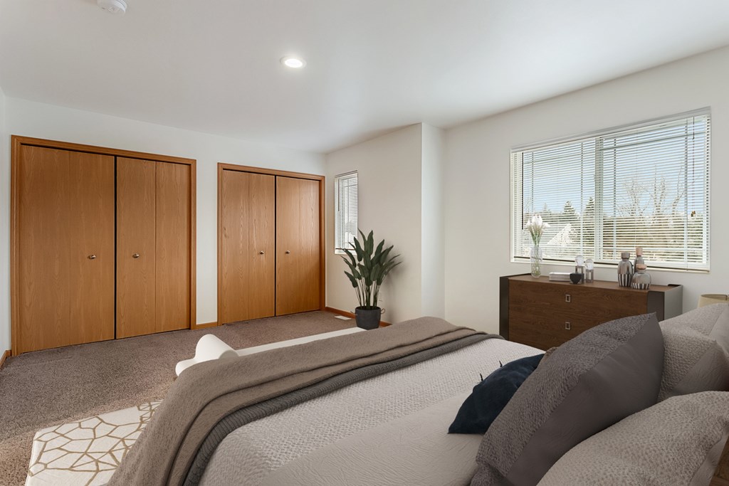 A bedroom with a large bed and a window with blinds.