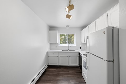 A kitchen with white cabinets and a white refrigerator.