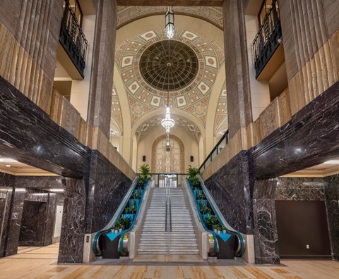 A grand staircase with a marble railing and steps leading to a circular ceiling.