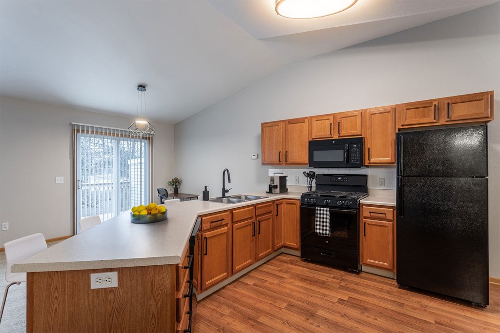 A kitchen with wooden cabinets and black appliances.
