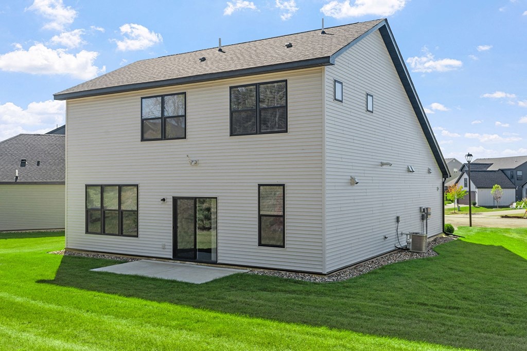the back of a white house with a lawn and a driveway