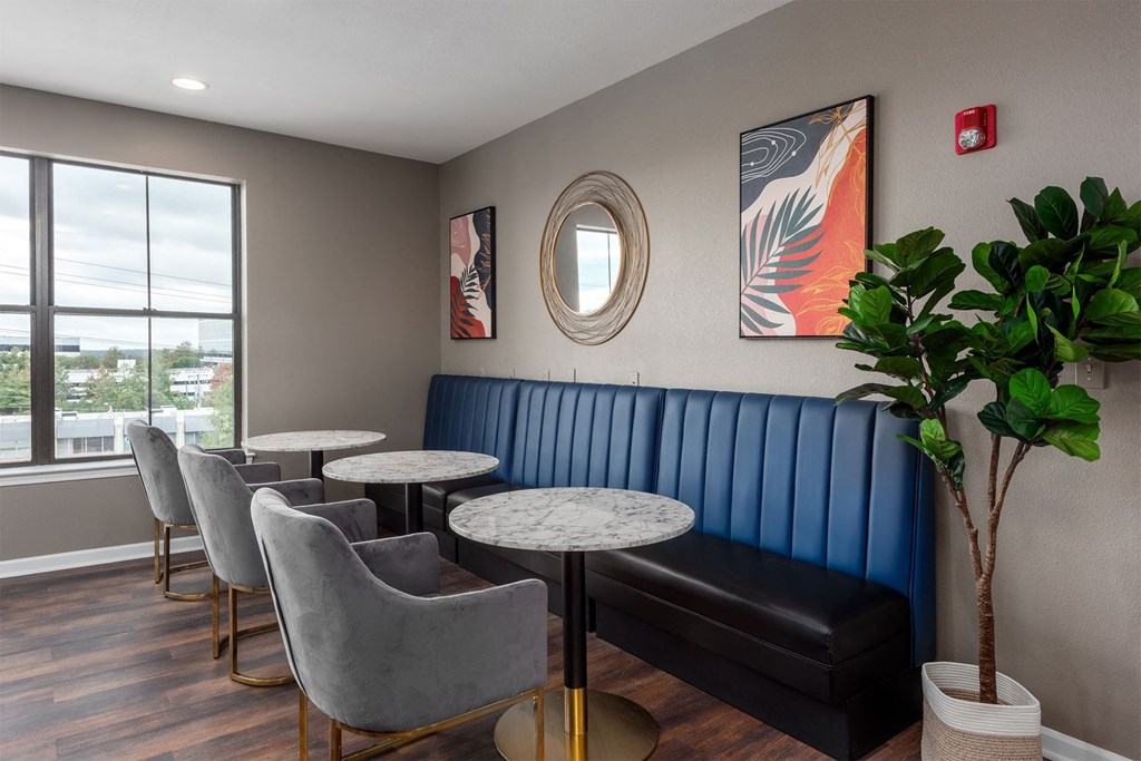 a seating area with a blue couch and tables and chairs