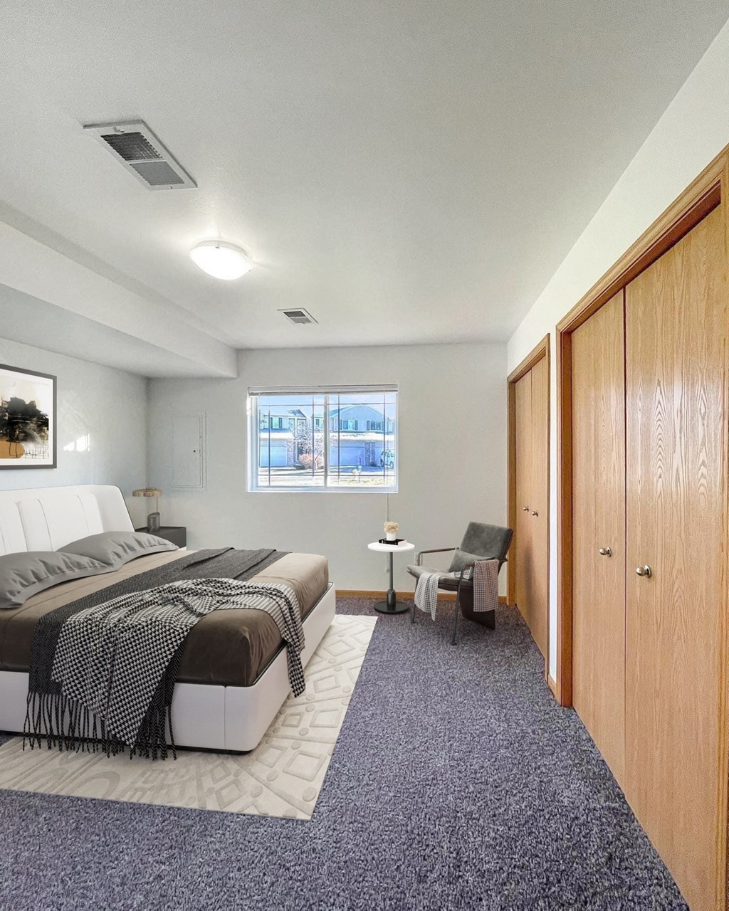 A bedroom with a bed, chair, and a window.