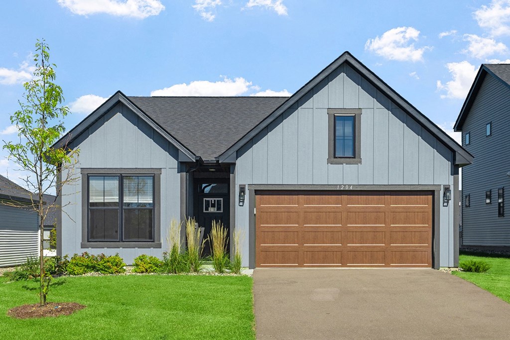 a home with a brown garage door in front of a green lawn