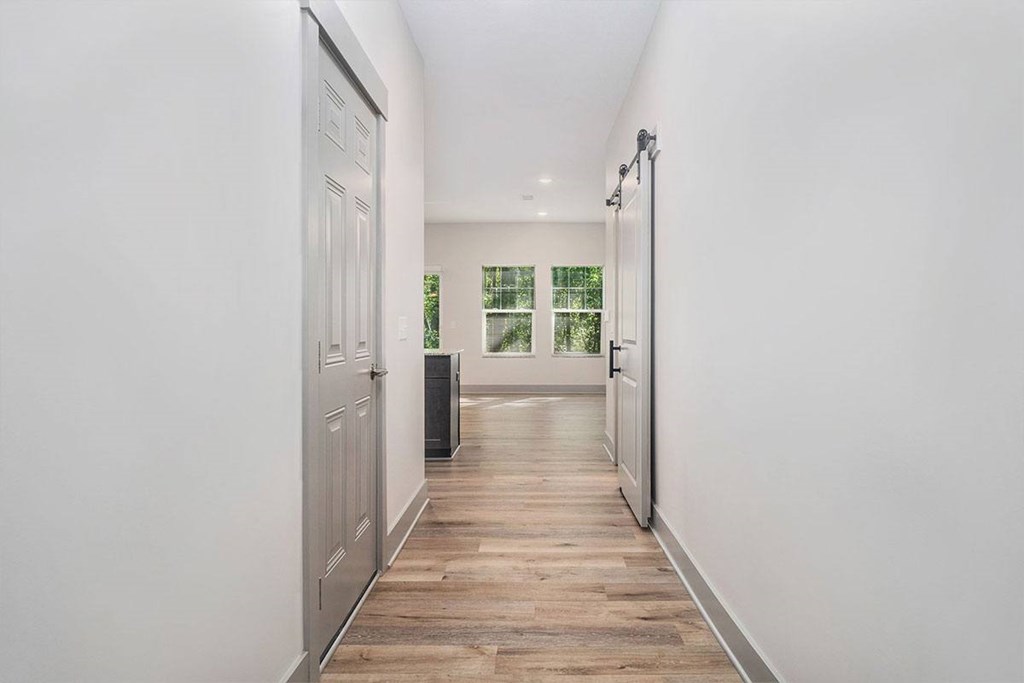 A long hallway with a door on the left and a window on the right.