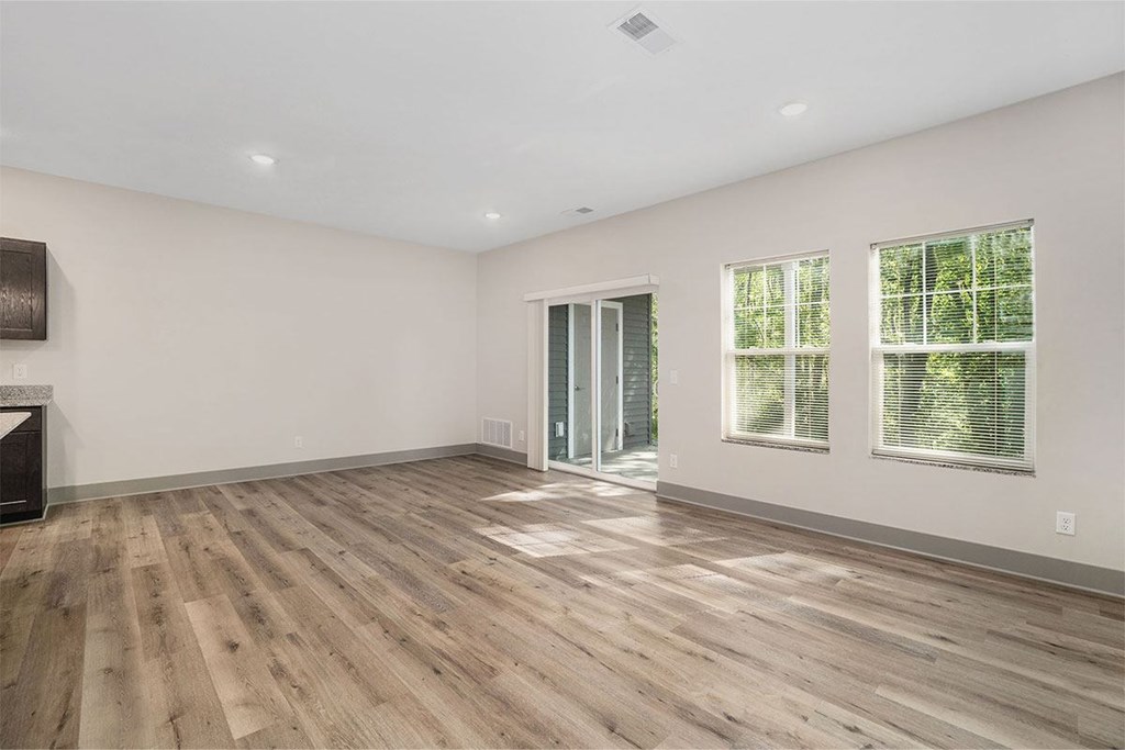 A room with a wooden floor and a window with blinds.