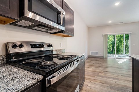 A modern kitchen with a stainless steel oven and microwave above a granite countertop.