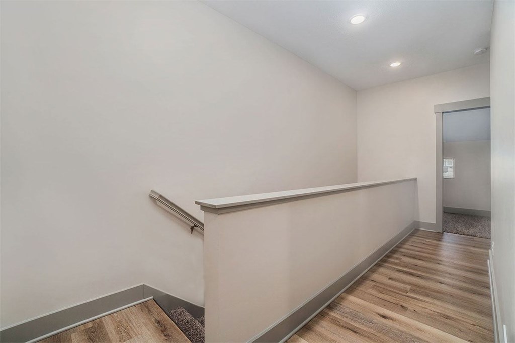 A room with a wooden floor and a white wall with a door on the right side.