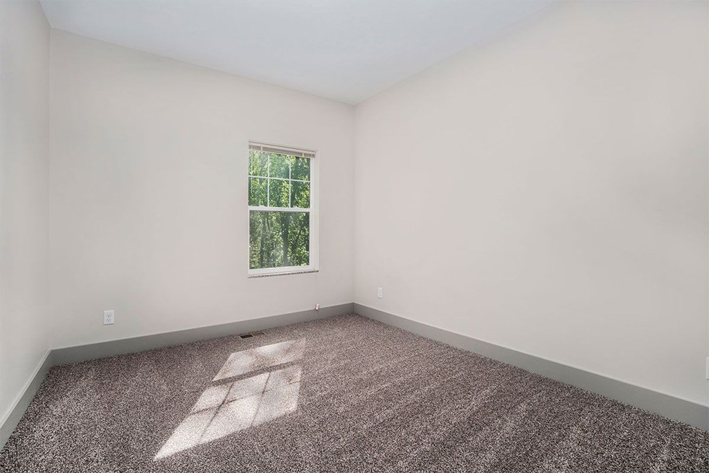 A room with a window and a carpeted floor.