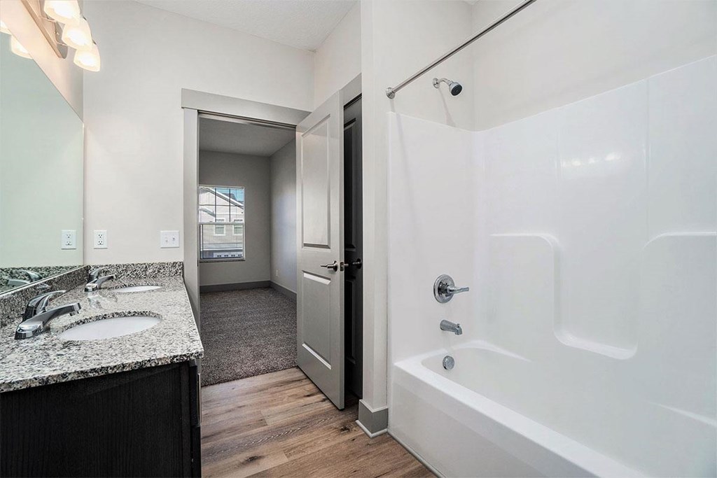 A bathroom with a white tub and a sink with a mirror above it.