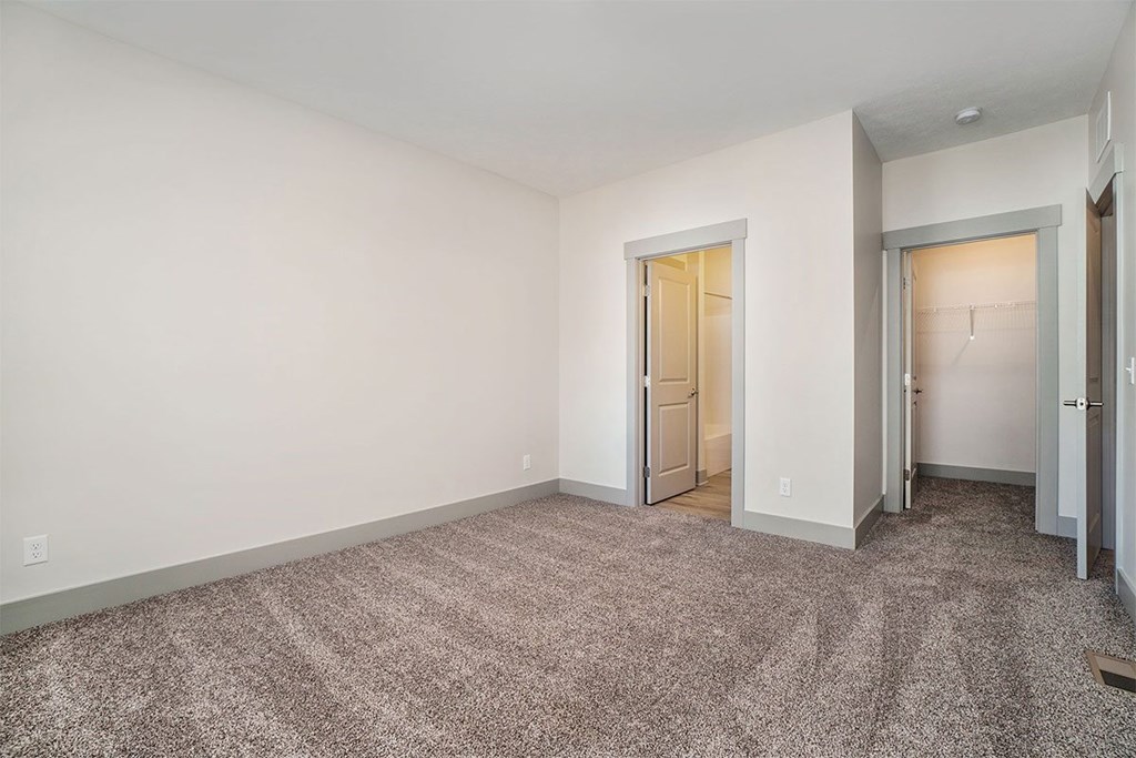 A room with carpeted floor and two doors.