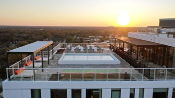 a view of the rooftop of a building with a pool and a sunset