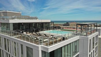 a view of the rooftop of a high rise building with a pool and the ocean