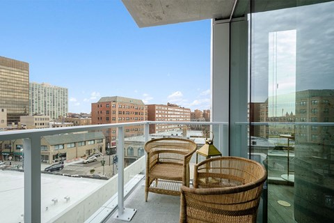 a balcony with wicker chairs and a view of the city