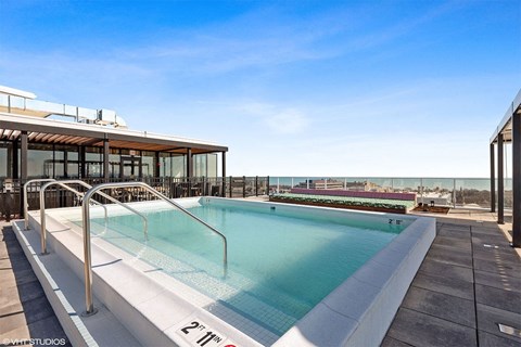 a pool on the roof of a building with the ocean in the background