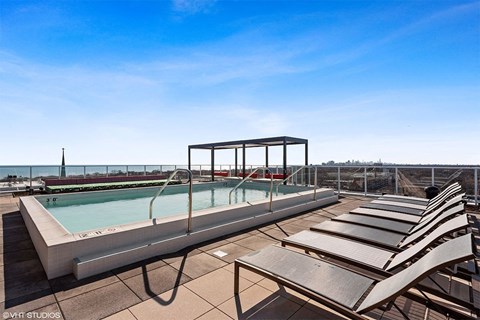 a swimming pool on the roof of a building with lounge chairs