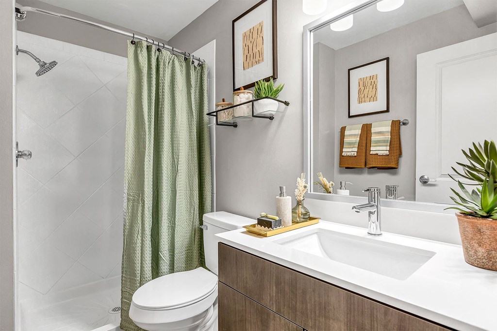 a bathroom with a toilet sink and shower and a mirror