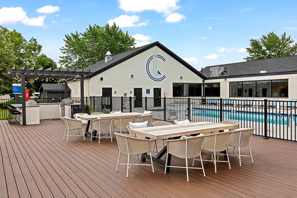 a patio with tables and chairs next to a swimming pool