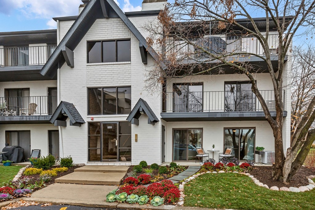 the front of a white house with a yard and a tree