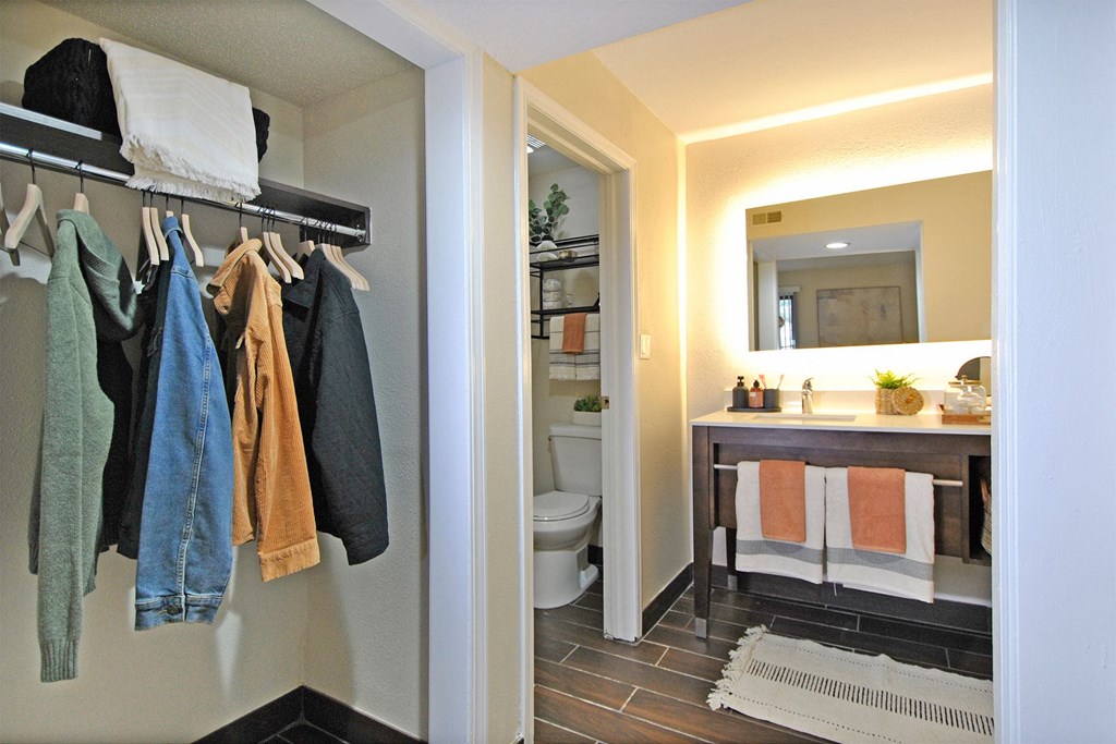 a view of a bathroom and a closet with towels and a sink and a toilet