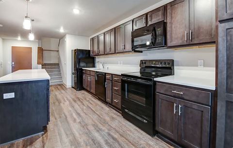 spacious apartment kitchen with dark brown cabinets black appliances and an island