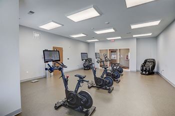 a workout room with exercise bikes and a tv