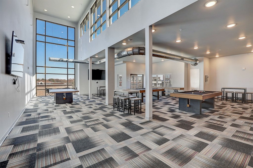 a game room with tables and a wall of windows