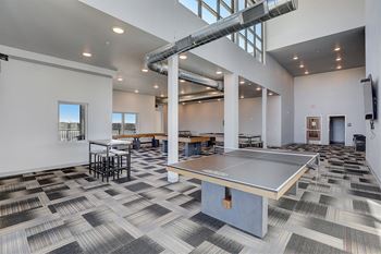 a ping pong table in a room with tables and chairs