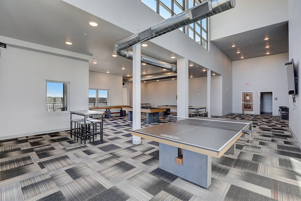 a ping pong table in a room with tables and chairs