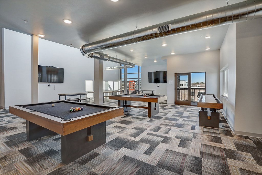 a game room with two pool tables and two televisions