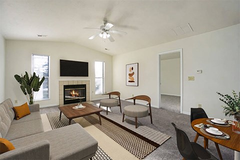 A living room with a grey couch, a coffee table, a fireplace, and a ceiling fan.