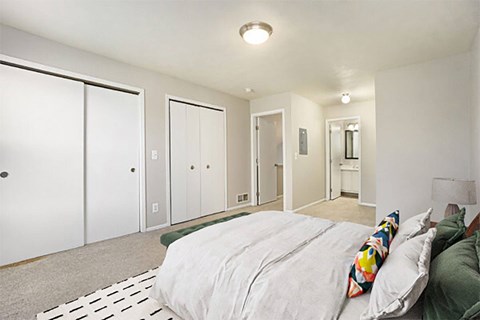 A bedroom with a bed, a couch, and a mirror.