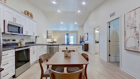 A wide angle shot of the kitchen and dining area showcasing vaulted ceilings.