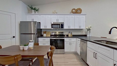 A kitchen with a table and chairs in front of it.