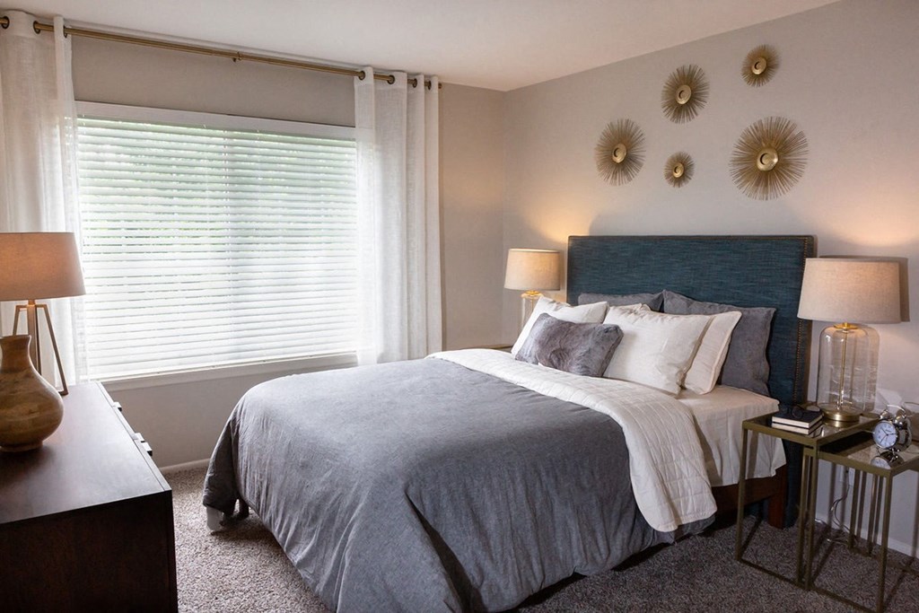 a bedroom with a bed and two mirrors on the wall