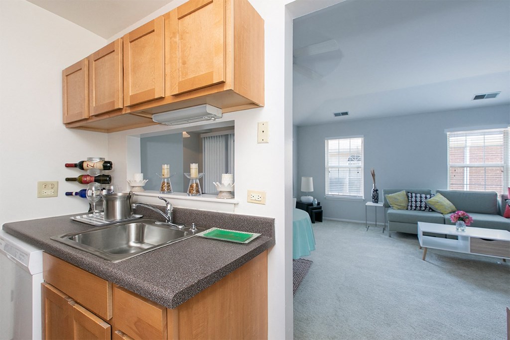 a kitchen with wood cabinets and a sink and a living room