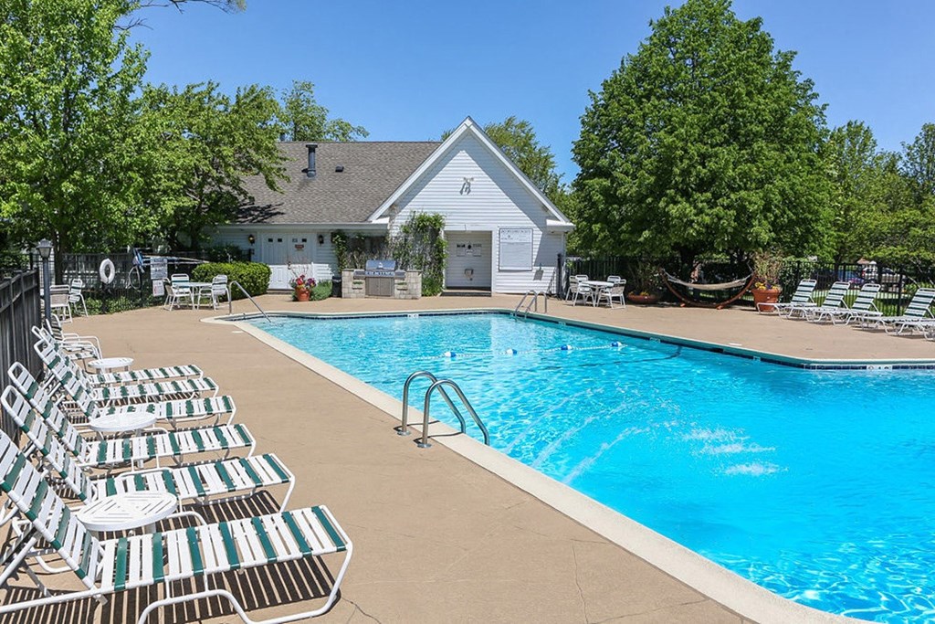 a swimming pool with chairs around it and a house in the background