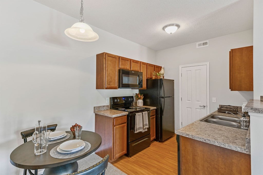 A kitchen with a black refrigerator and wooden cabinets.