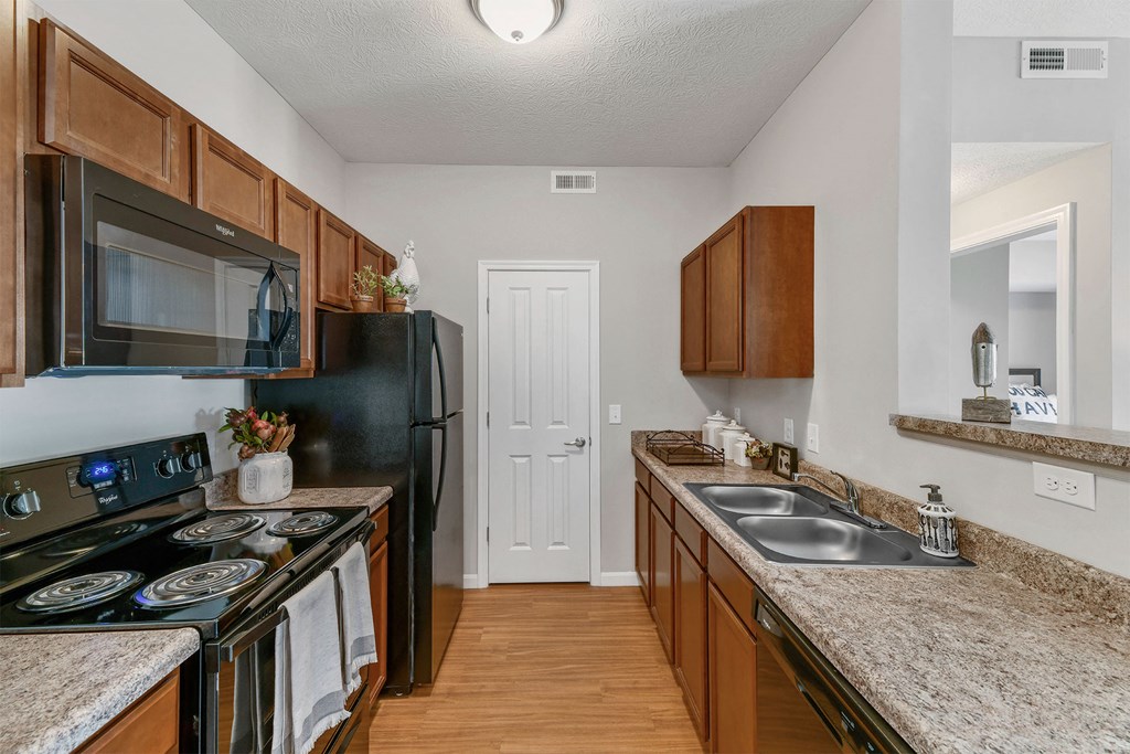 A kitchen with a black refrigerator and wooden cabinets.