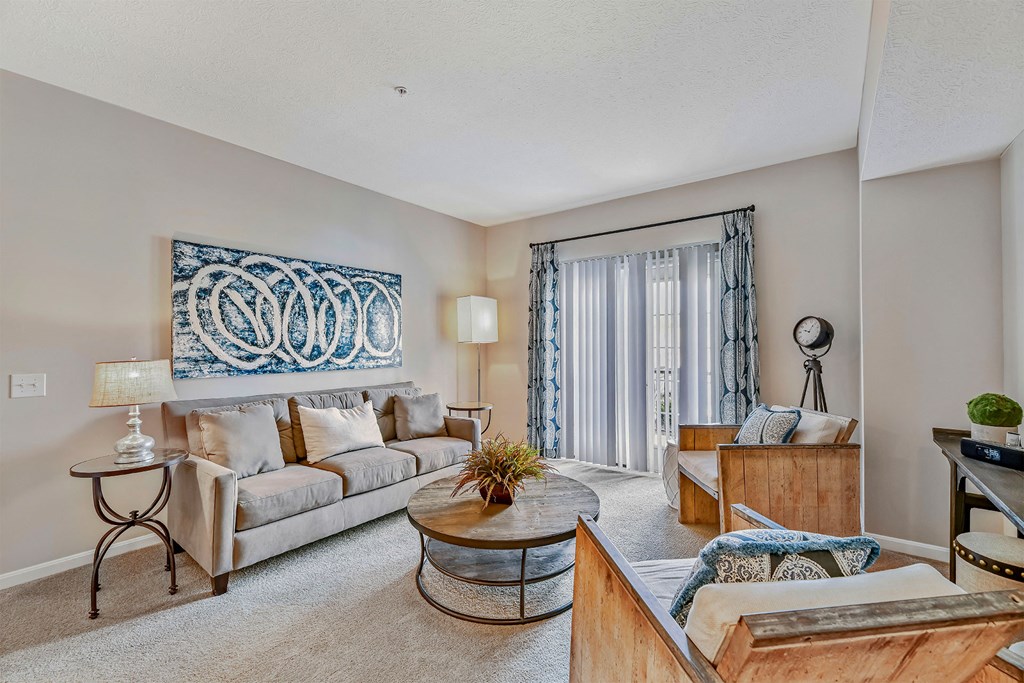 A living room with a grey couch, a coffee table, and a large tapestry hanging on the wall.