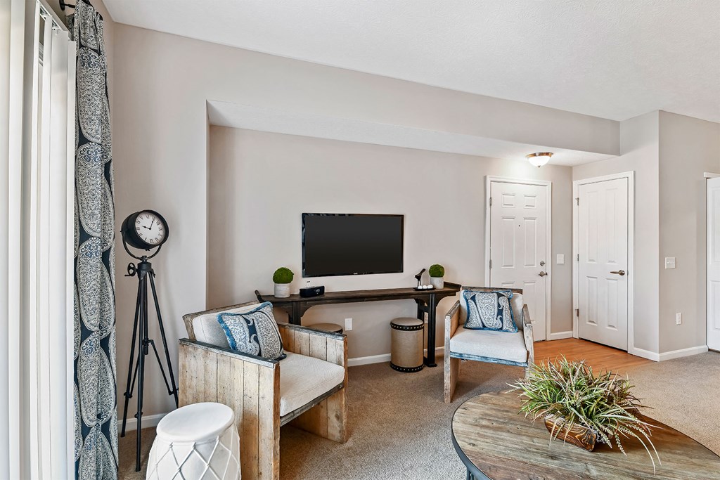 A living room with a television, two chairs, a table, and a plant.