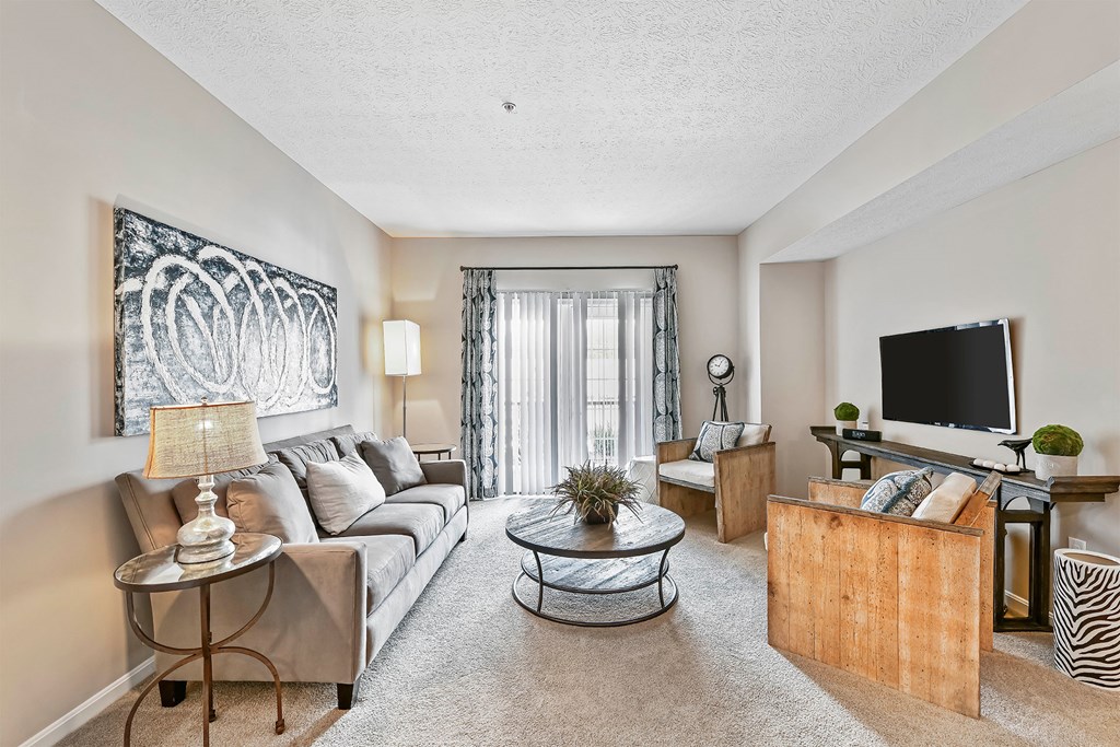 A living room with a grey couch, a glass coffee table, and a television.