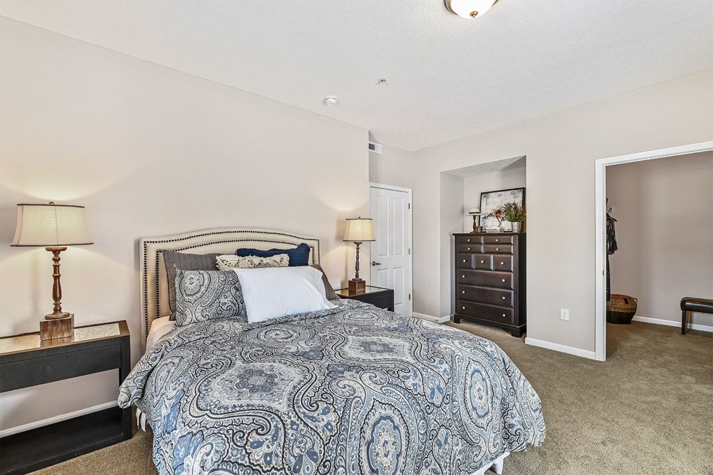 A bedroom with a large bed and a nightstand with a lamp.