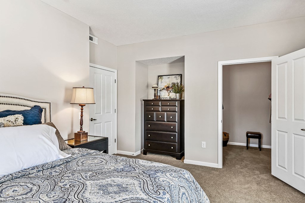 A bedroom with a bed, dresser, and a lamp.
