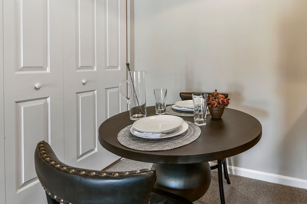 A black leather chair sits in front of a white door with a table set for two.