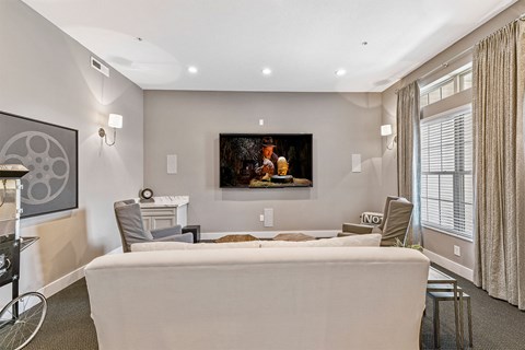 A living room with a grey couch and a painting on the wall.