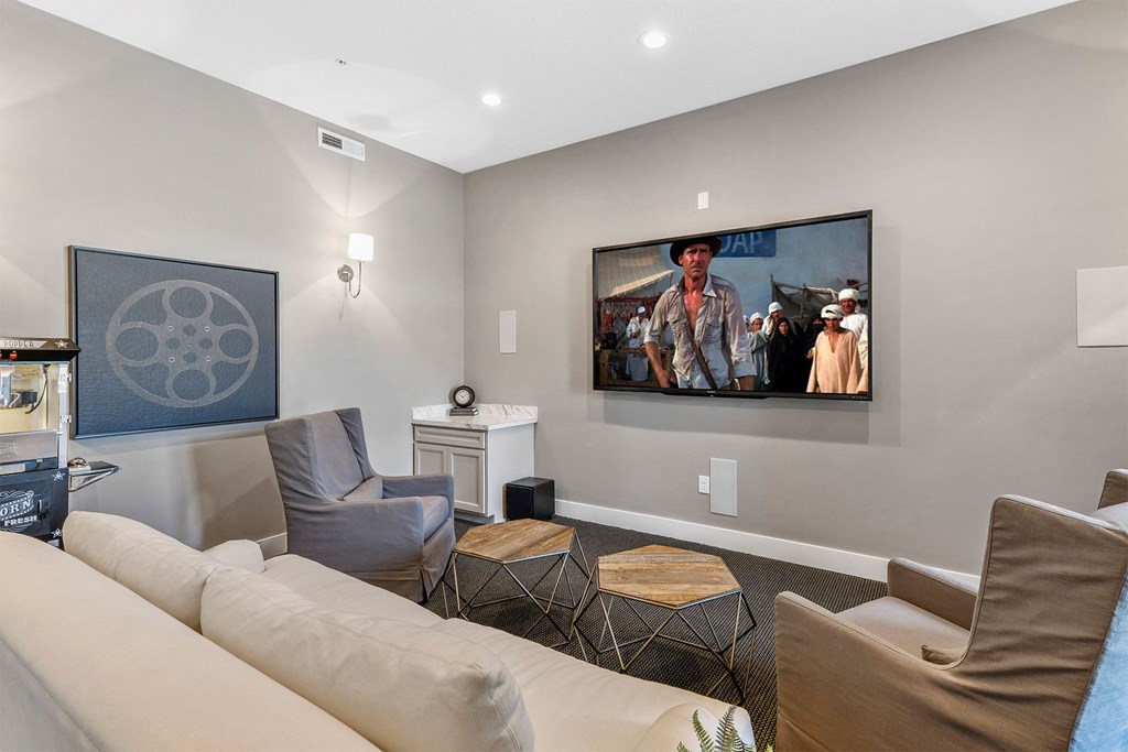 A living room with a large screen TV and a painting of a cowboy on the wall.