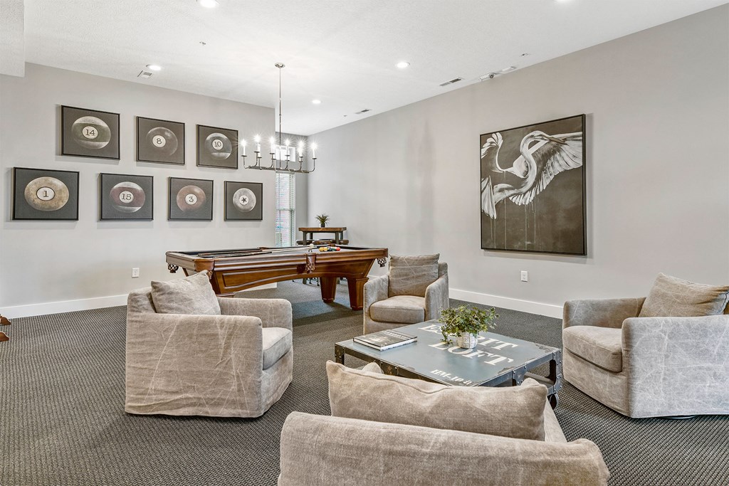 A living room with a grey carpet and a chandelier.